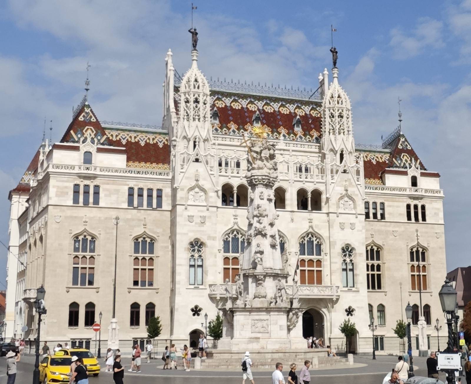 The restored neo-Gothic palace on Szentháromság tér: carved stone facade, patterned tiled roof, two turrets