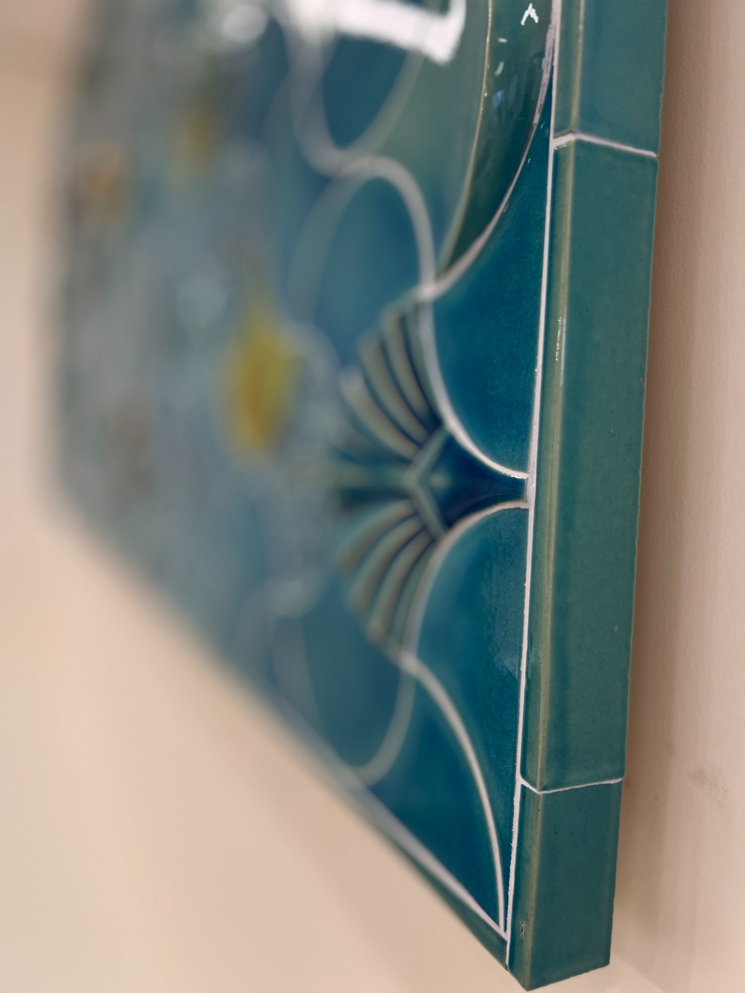 The edge of the ceramic wall seen from the side: relief celadon elements against the wall plane