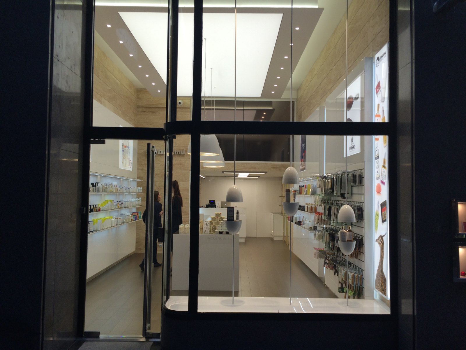 The double-height glazed shopfront seen from outside at night, the lit interior visible through it